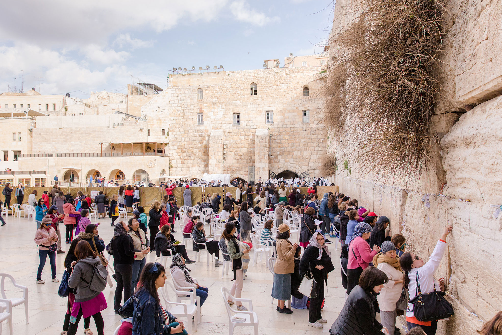 Crowds at the women's section of the Western Wall on a sunny day.