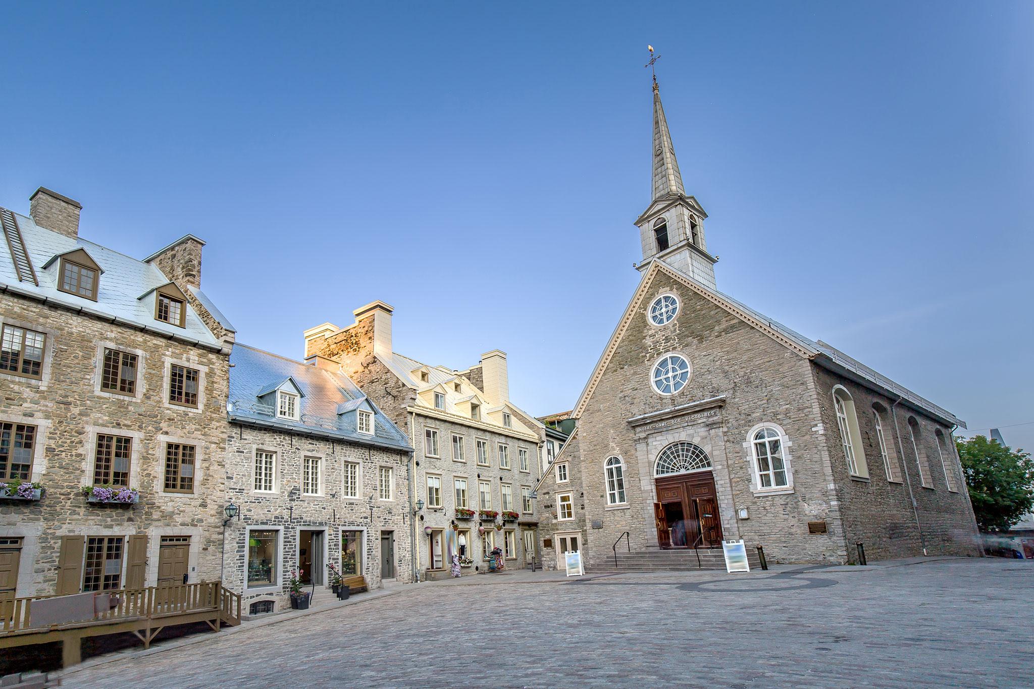 Historic stone church and surrounding buildings in a quiet European-style town square.