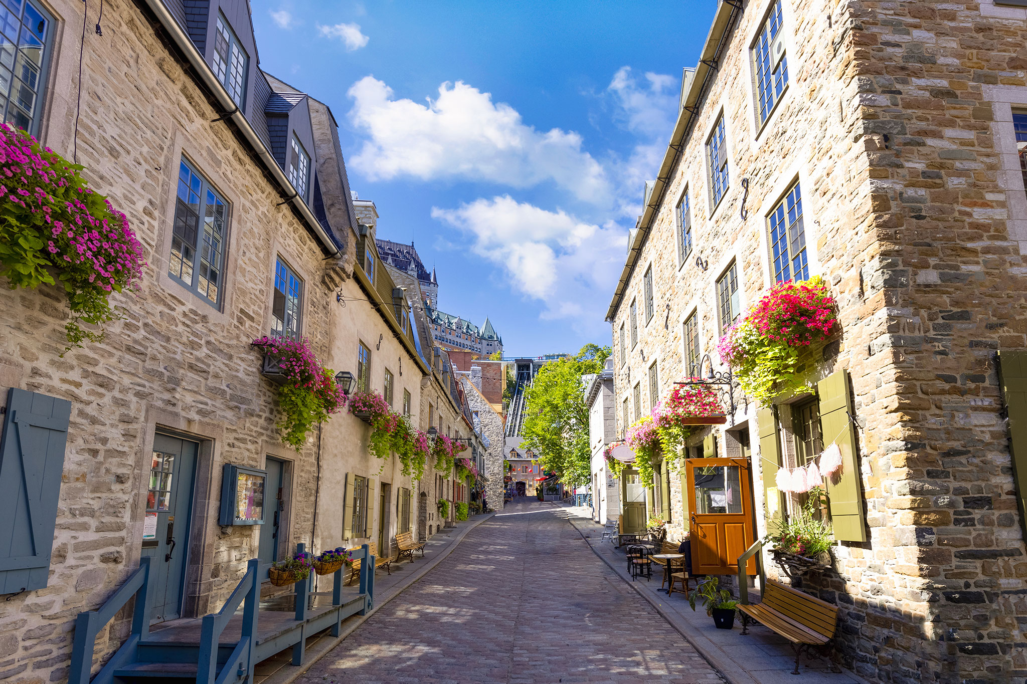 Bright, sunny alleyway with old-world architecture and flower-filled window boxes in a European-style town.