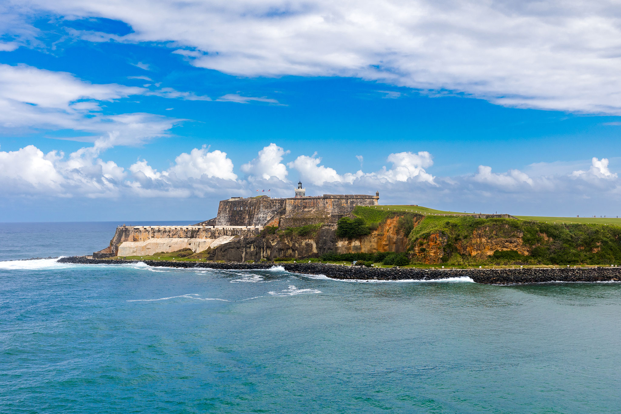 Castillo San Felipe del Morro, a stone fort perched on a grassy cliffside with waves crashing below.