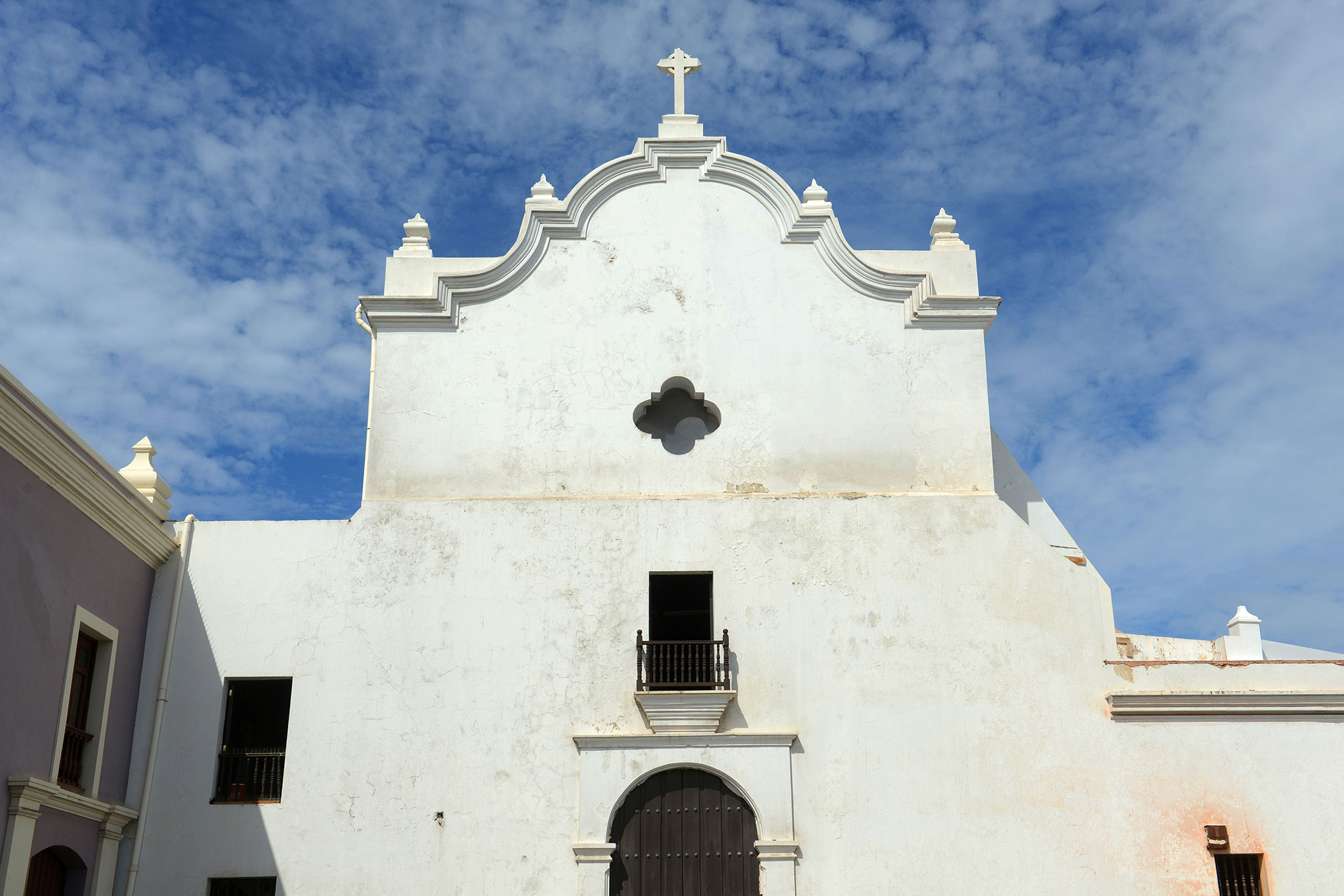 Stucco church front featuring Spanish colonial architecture and decorative trim.
