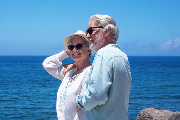 A smiling couple with the ocean in the background