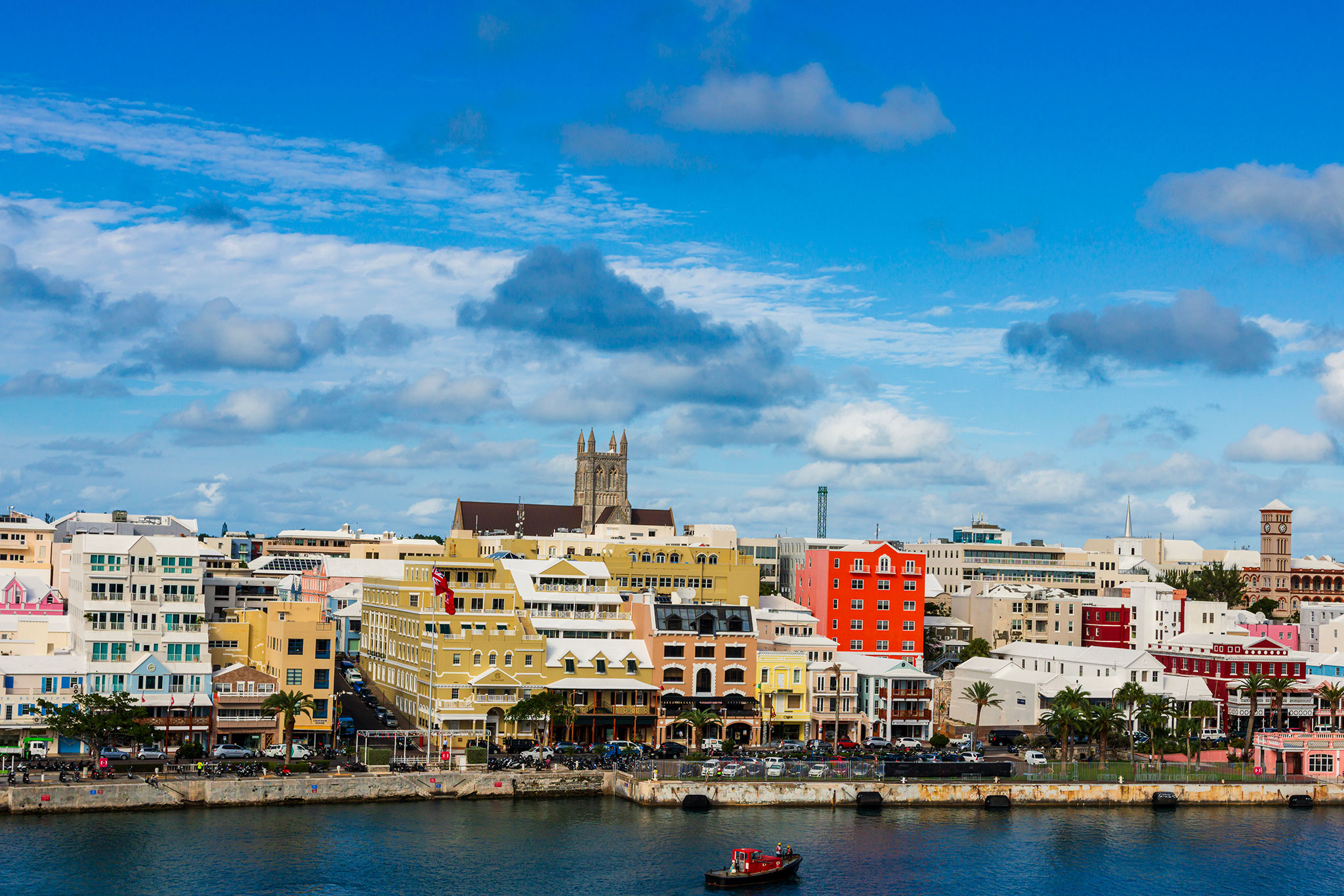 Waterfront scene of Hamilton’s iconic Front Street lined with pastel buildings under a bright blue sky.