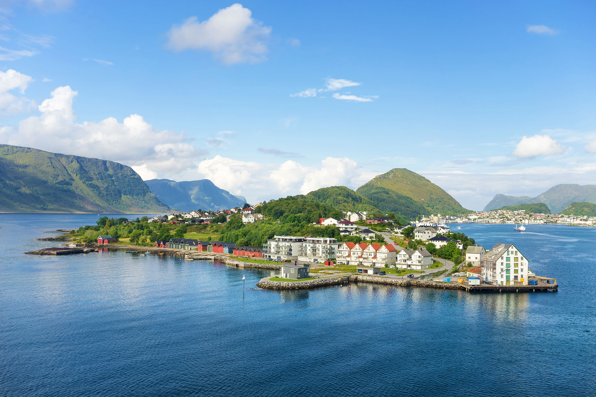 Scenic coastal town of Alesund in Norway surrounded by fjords and green mountains.