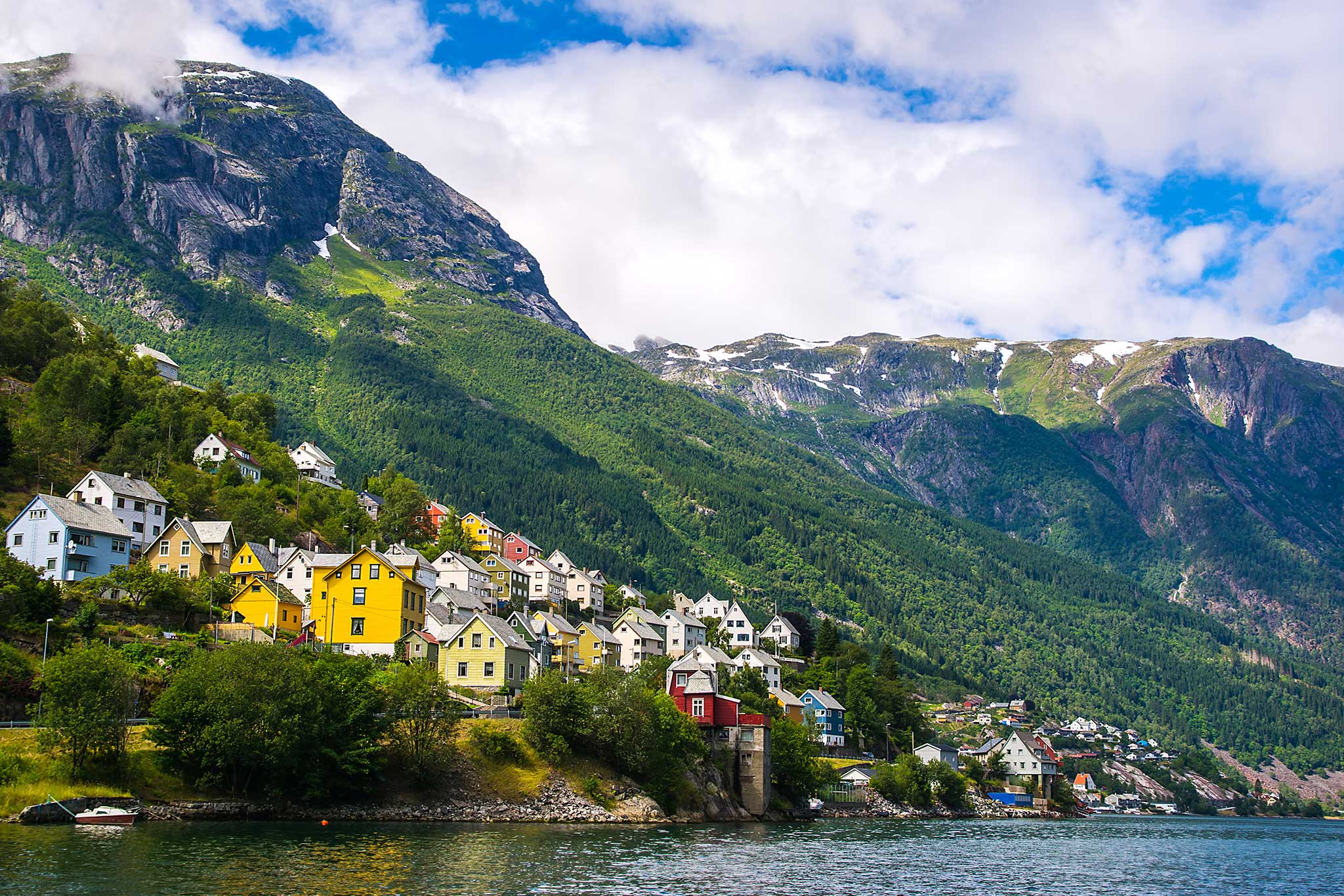 Vibrant homes overlooking the fjord in Odda, nestled against dramatic mountain cliffs.