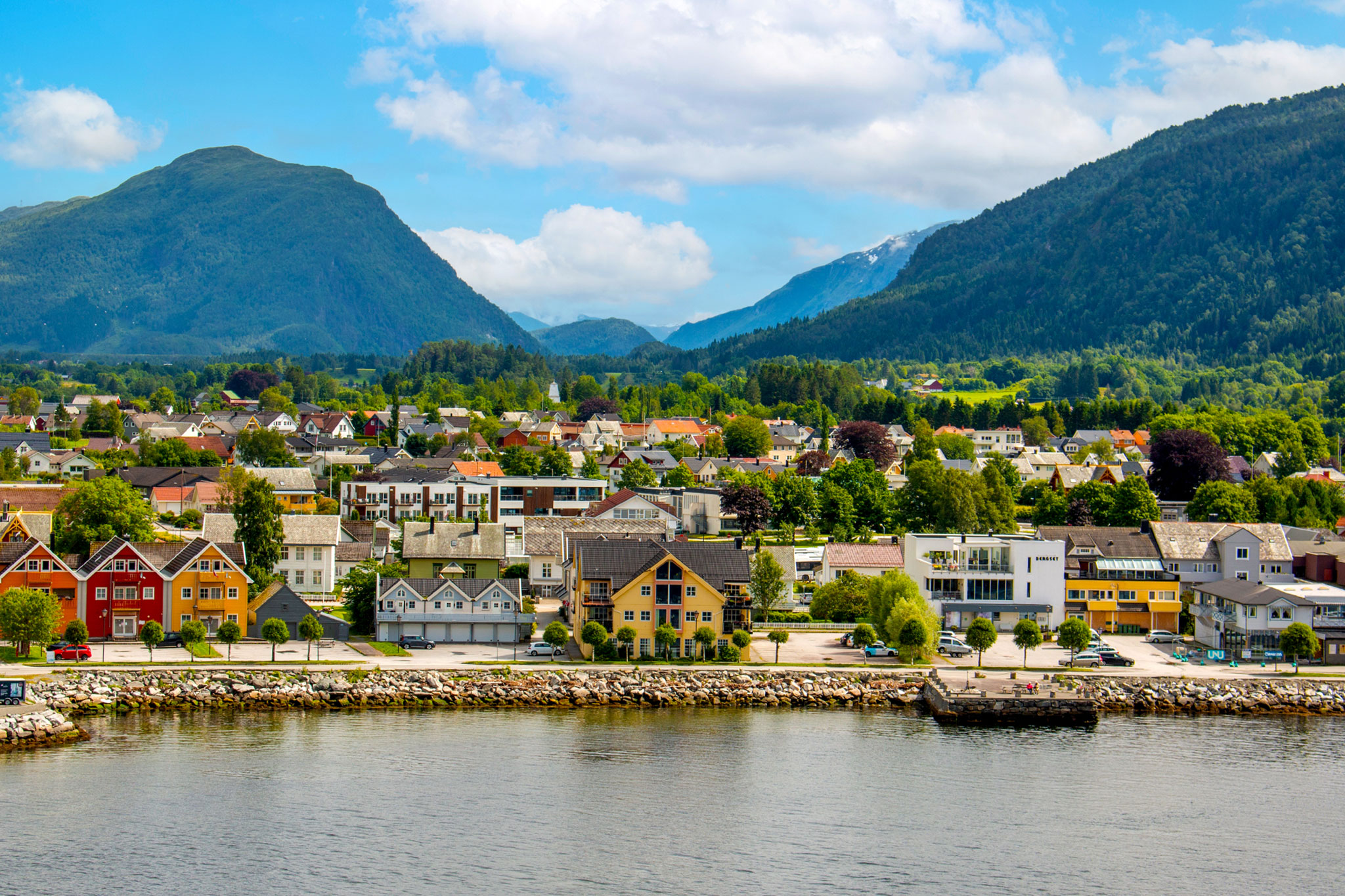 Charming town of Nordfjordeid, with a mix of traditional wooden houses and modern architecture, set against the fjord and rolling mountains.
