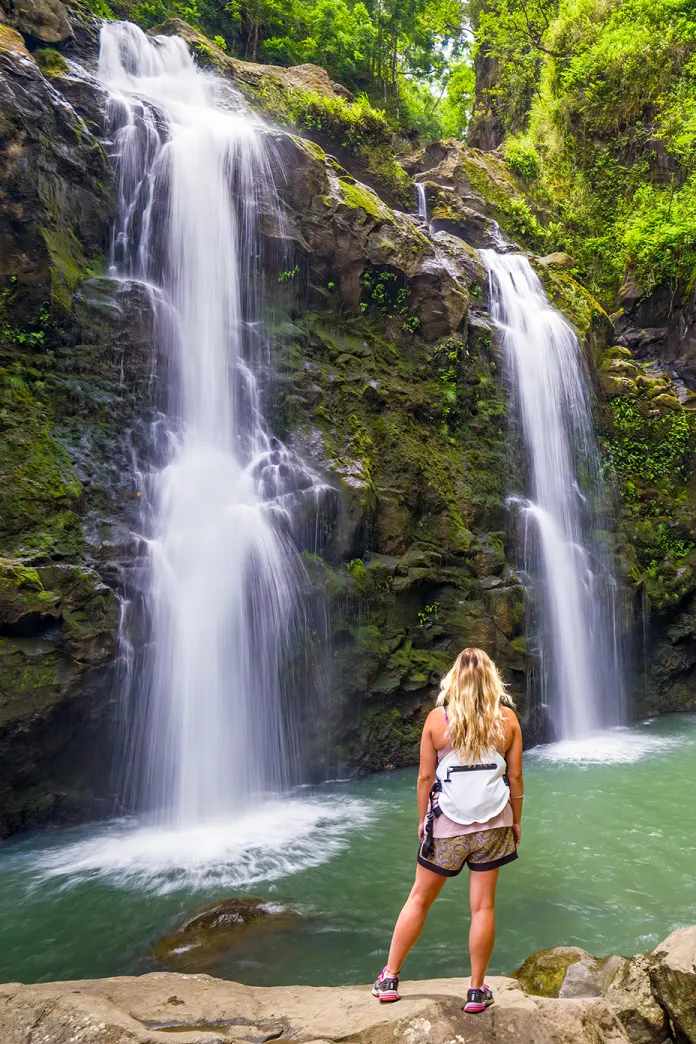 Woman standing on a rock looking at two beautiful waterfalls