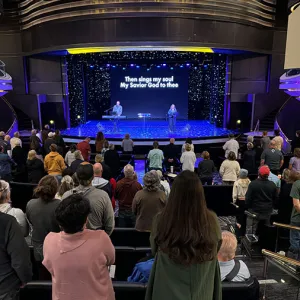 People singing on a stage in an auditorium filled with people