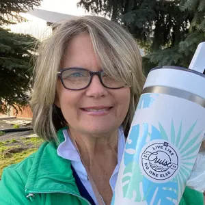 Smiling woman holding up a water bottle with the Live Like No One Else Cruise logo on it