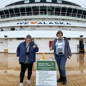 Two smiling travelers standing on the cruise ship deck
